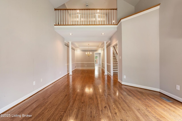 7808 Grenoble Ln, Prospect, KY 40059 - unfurnished living room with wood finished floors, stairs, a chandelier, baseboards, and a towering ceiling