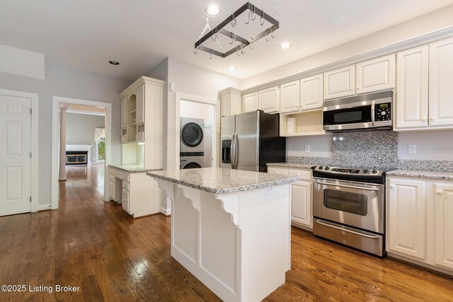 7808 Grenoble Ln, Prospect, KY 40059 - kitchen with appliances with stainless steel finishes, stacked washer / drying machine, dark wood-type flooring, light stone countertops, and recessed lighting