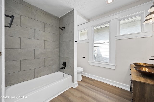 full bathroom featuring toilet, vanity, shower / tub combination, wood finished floors, and baseboards