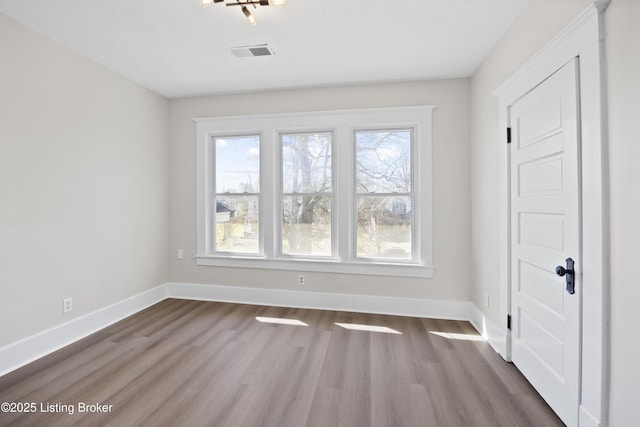 unfurnished room with dark wood-style floors, visible vents, and baseboards