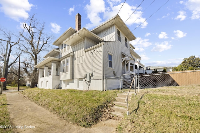 view of side of home with a lawn, a gate, fence, and a chimney