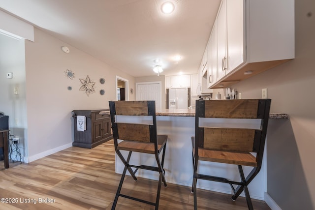 432 Four Seasons Rd, Falls Of Rough, KY 40119 - kitchen with white fridge with ice dispenser, white cabinetry, a peninsula, a breakfast bar area, and light wood finished floors