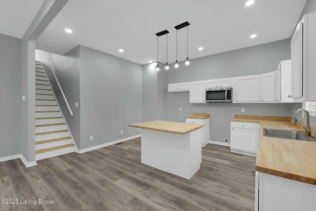 2203 Date St, Louisville, KY 40210 - kitchen with stainless steel microwave, wooden counters, a sink, white cabinets, and wood finished floors
