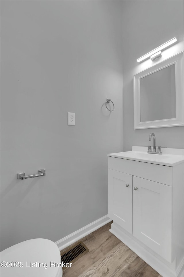 2203 Date St, Louisville, KY 40210 - half bathroom with toilet, vanity, wood finished floors, baseboards, and visible vents