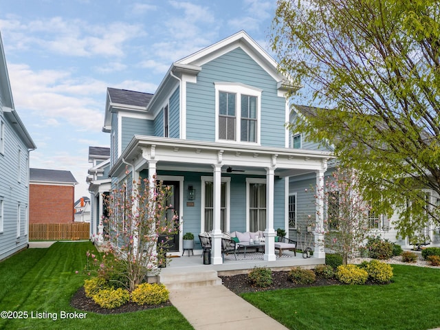view of front of property featuring a porch, fence, a front lawn, and an outdoor hangout area