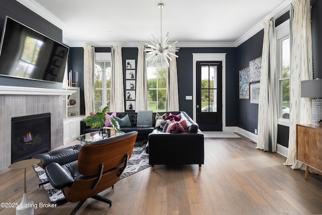 living area with ornamental molding, baseboards, wood finished floors, and a fireplace
