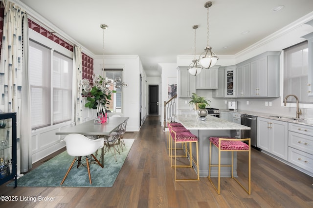 kitchen with ornamental molding, glass insert cabinets, a kitchen bar, stainless steel dishwasher, and a sink