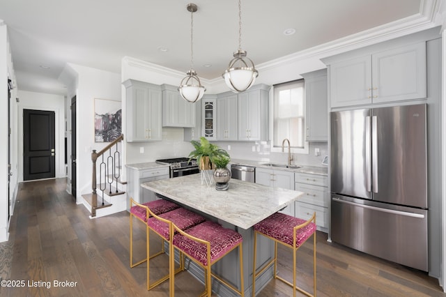 kitchen featuring glass insert cabinets, a breakfast bar, a sink, stainless steel appliances, and dark wood-style floors