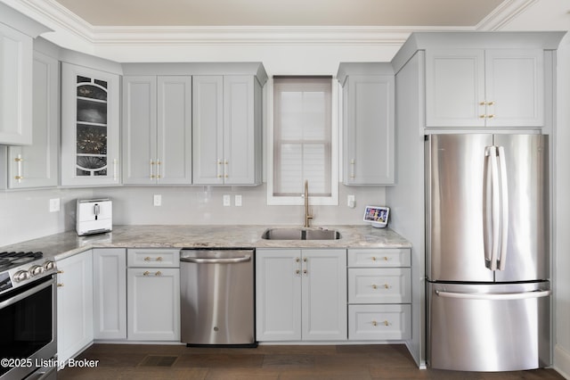 kitchen featuring glass insert cabinets, light stone countertops, dark wood-type flooring, stainless steel appliances, and a sink