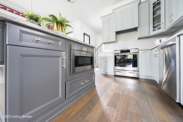 kitchen featuring gray cabinets, glass insert cabinets, stainless steel electric range oven, dark wood finished floors, and fridge