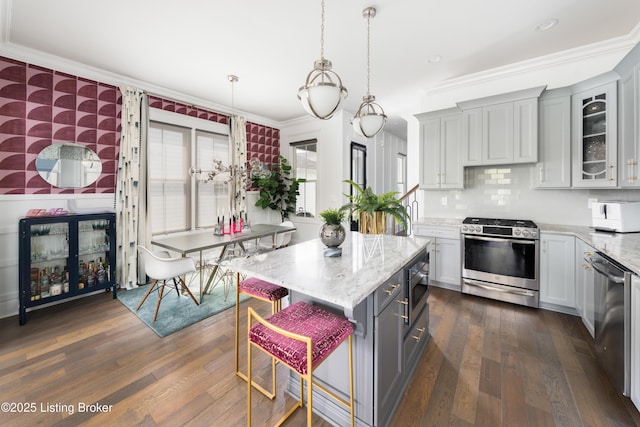 kitchen featuring dark wood-type flooring, ornamental molding, and stainless steel appliances