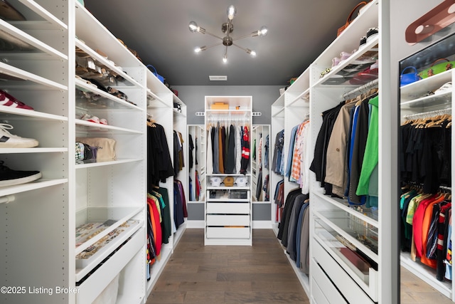 walk in closet featuring a chandelier, visible vents, and wood finished floors