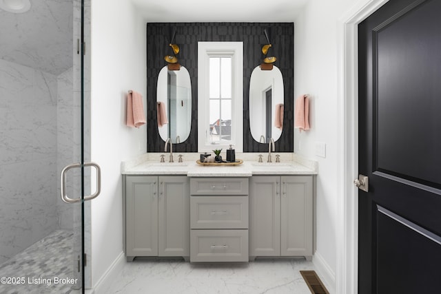 bathroom featuring marble finish floor, baseboards, a sink, and a marble finish shower