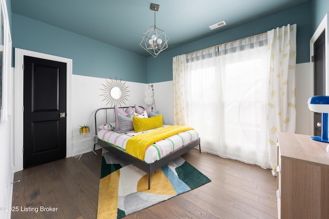 bedroom with visible vents, a notable chandelier, and hardwood / wood-style floors