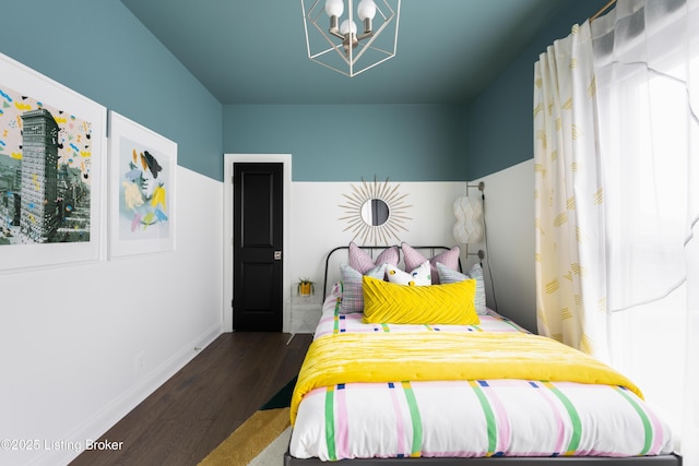 bedroom with a notable chandelier, baseboards, and wood finished floors