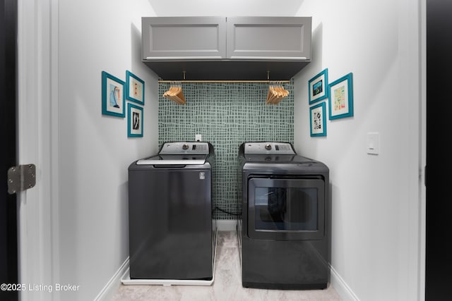 laundry room with washer and clothes dryer, baseboards, and cabinet space