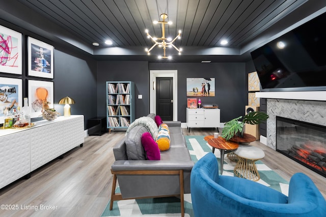 interior space with a tiled fireplace, a tray ceiling, wooden ceiling, and wood finished floors