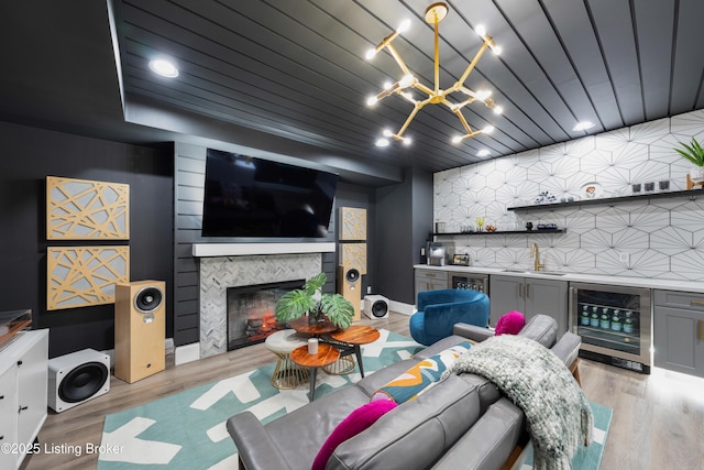 living room featuring light wood-style flooring, an inviting chandelier, indoor bar, and wine cooler