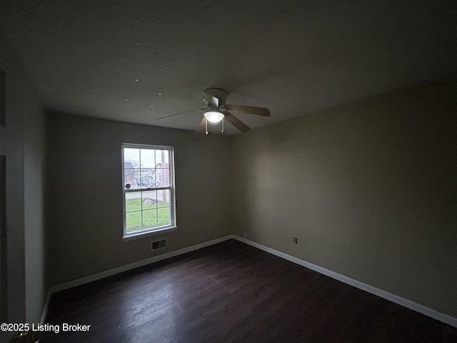 unfurnished room featuring dark wood-style floors, visible vents, baseboards, and a ceiling fan