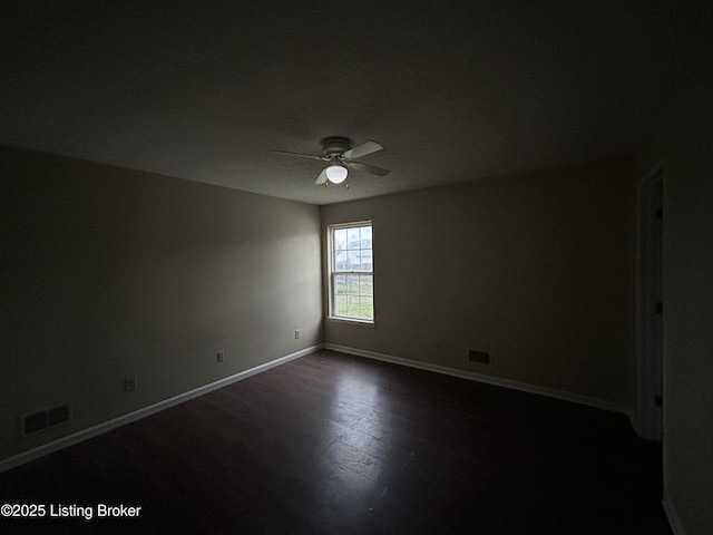 empty room featuring baseboards, dark wood-style flooring, visible vents, and a ceiling fan