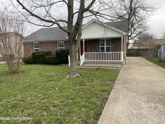 view of front of house with a front yard, concrete driveway, fence, brick siding, and a porch