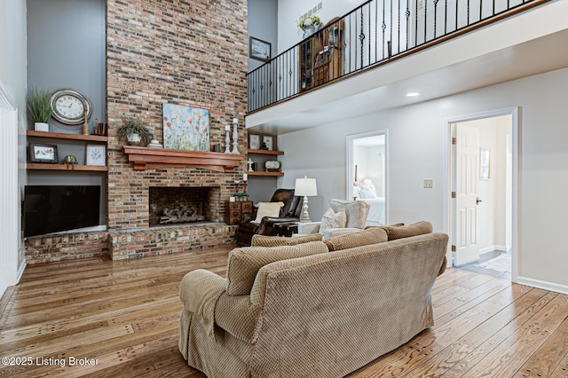 1014 Old Mill Stream Ln, Shepherdsville, KY 40165 - living area featuring a towering ceiling, wood-type flooring, baseboards, and a brick fireplace