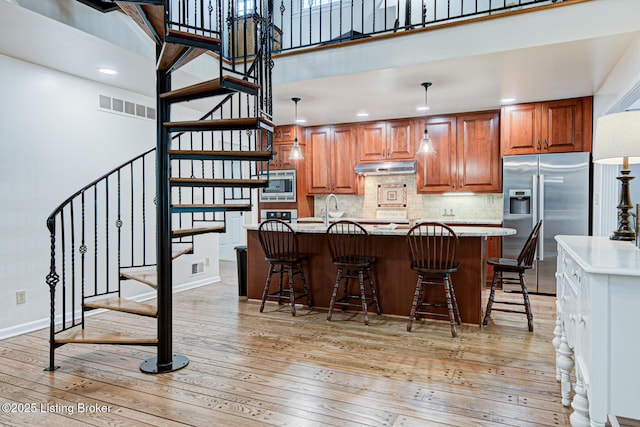 1014 Old Mill Stream Ln, Shepherdsville, KY 40165 - kitchen with appliances with stainless steel finishes, light wood finished floors, a towering ceiling, under cabinet range hood, and recessed lighting