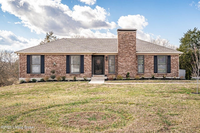 ranch-style house featuring brick siding, a shingled roof, a chimney, and a front yard