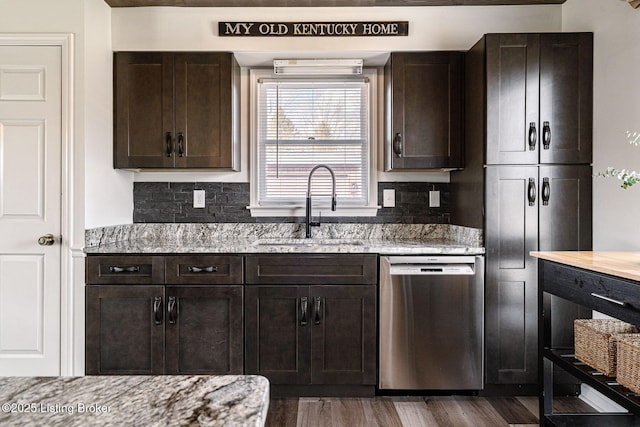 kitchen with dark brown cabinetry, backsplash, dishwasher, a sink, and light stone counters