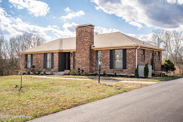 single story home with brick siding, a shingled roof, a chimney, and a front yard