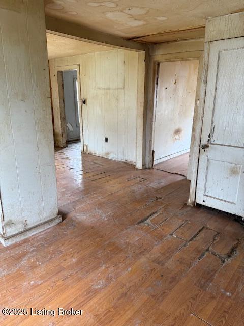 unfurnished room with wood walls and wood-type flooring