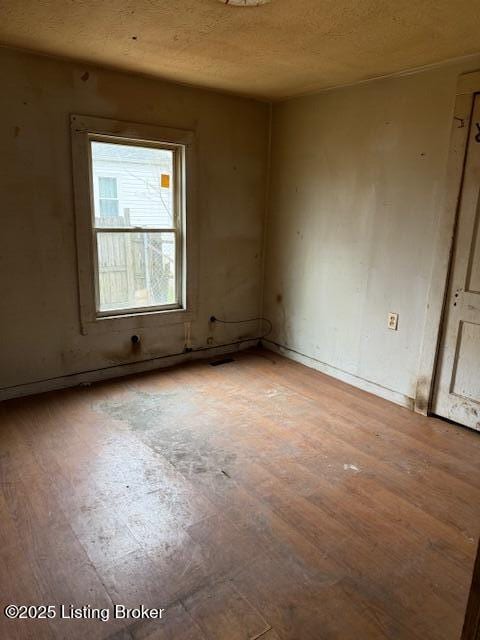 unfurnished room with a textured ceiling and wood finished floors