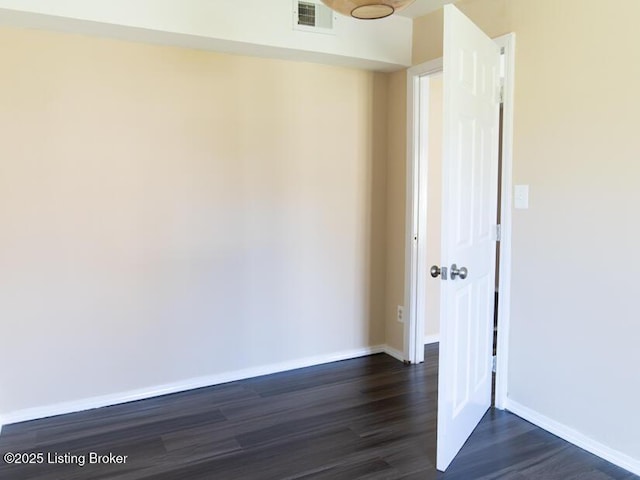 unfurnished room with dark wood-style floors, visible vents, and baseboards