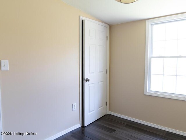 unfurnished bedroom with baseboards, a closet, and dark wood-type flooring