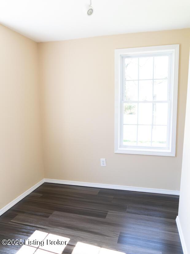 spare room featuring baseboards and dark wood finished floors
