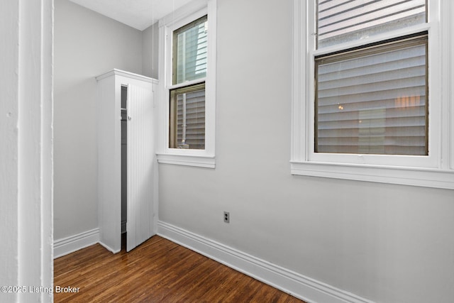 unfurnished room featuring baseboards and dark wood-style floors