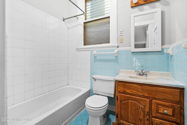 bathroom featuring vanity, shower / washtub combination, a wainscoted wall, toilet, and tile walls