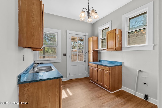 kitchen featuring light wood-style flooring, a sink, baseboards, and dark countertops