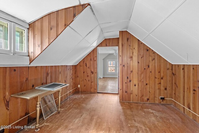 additional living space with wood walls, hardwood / wood-style flooring, and lofted ceiling