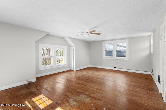 interior space with a textured ceiling, baseboards, a ceiling fan, and wood finished floors