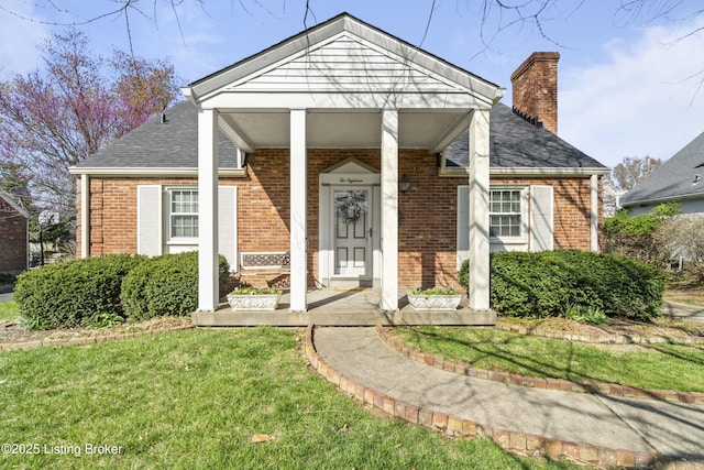 view of front of house with a front yard, brick siding, and a chimney