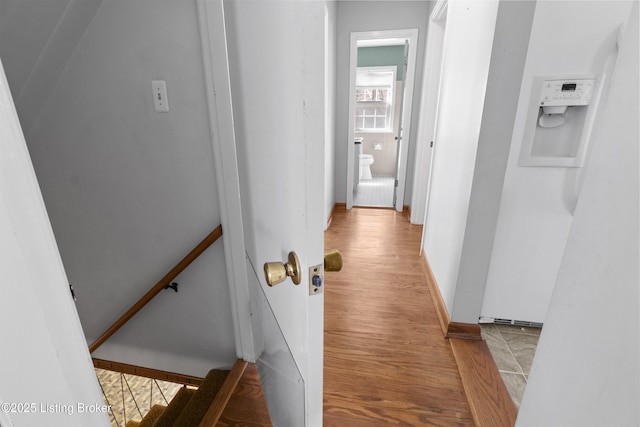 corridor with wood finished floors, baseboards, and an upstairs landing