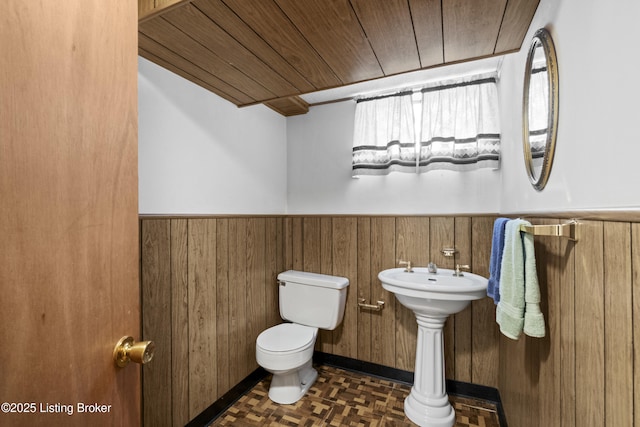 half bath featuring toilet, a wainscoted wall, wooden walls, and wood ceiling