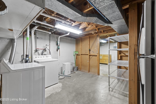unfinished basement featuring washer and dryer and freestanding refrigerator