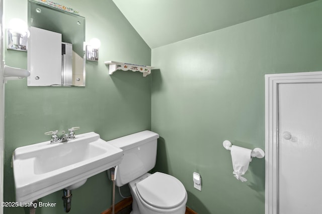 bathroom with a sink, toilet, and lofted ceiling