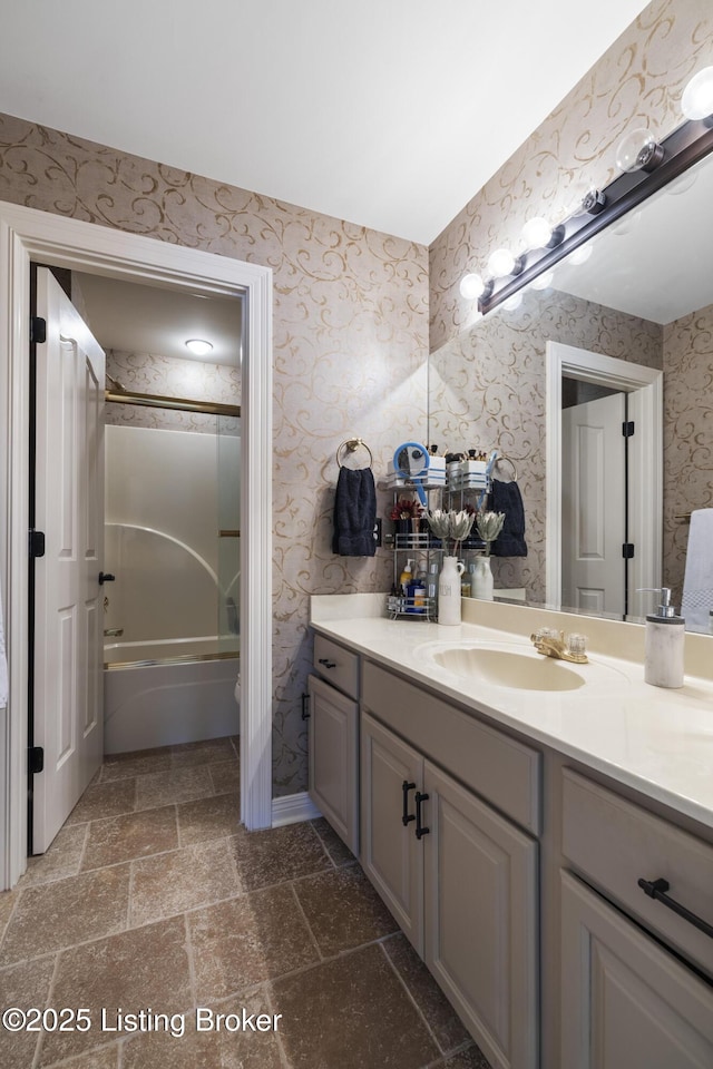 12206 Bridgeway Ct, Sellersburg, IN 47172 - full bathroom with wallpapered walls, vanity, stone finish floor, and bath / shower combo with glass door