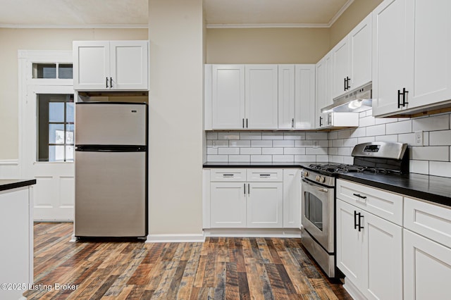 kitchen with dark countertops, crown molding, under cabinet range hood, and stainless steel appliances