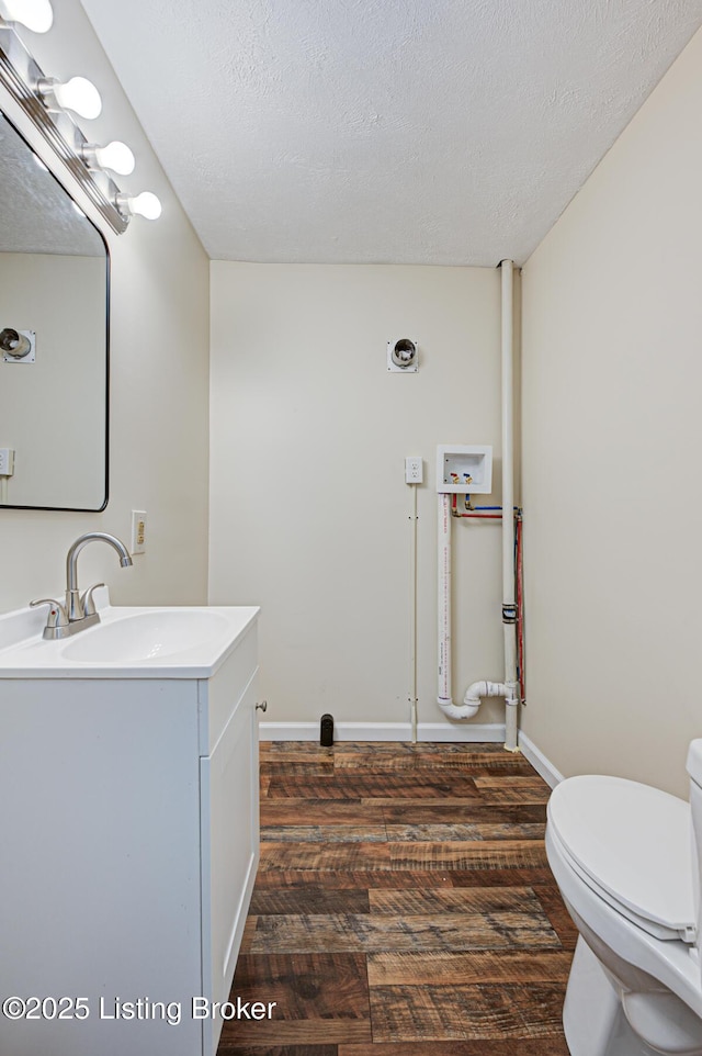 half bathroom featuring a textured ceiling, wood finished floors, and vanity