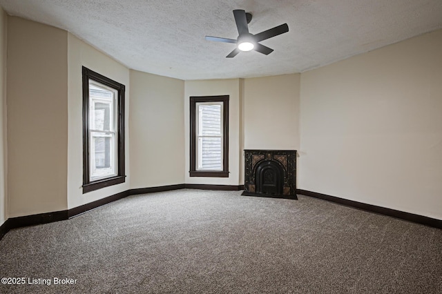 unfurnished living room featuring baseboards, a ceiling fan, carpet floors, and a textured ceiling