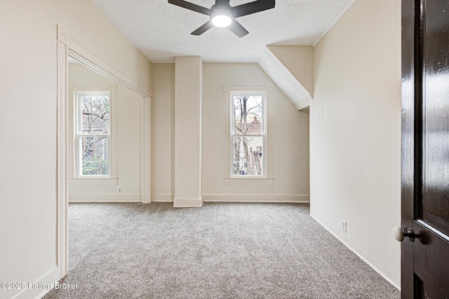 bonus room with baseboards, carpet flooring, a textured ceiling, and a ceiling fan